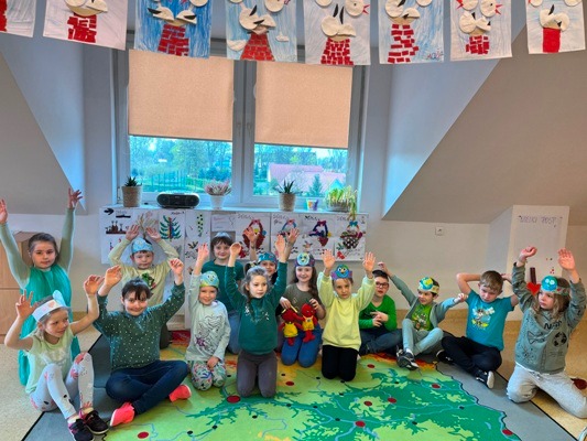 Grupa dzieci pozuje do zdjęcia w strojach niebieskich i zielonych