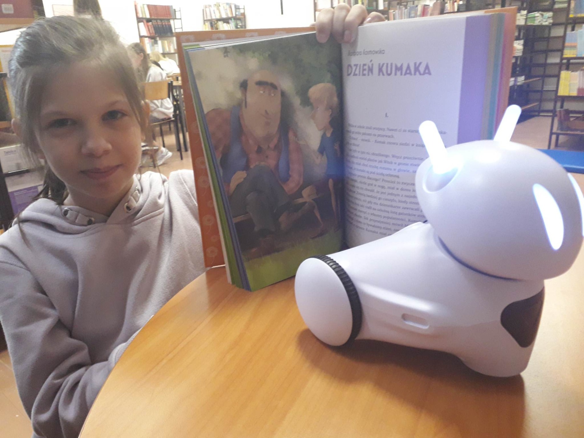 Ola Soska z książką z opowiadaniem "Dzień Kumaka" oraz z robotem Photon
