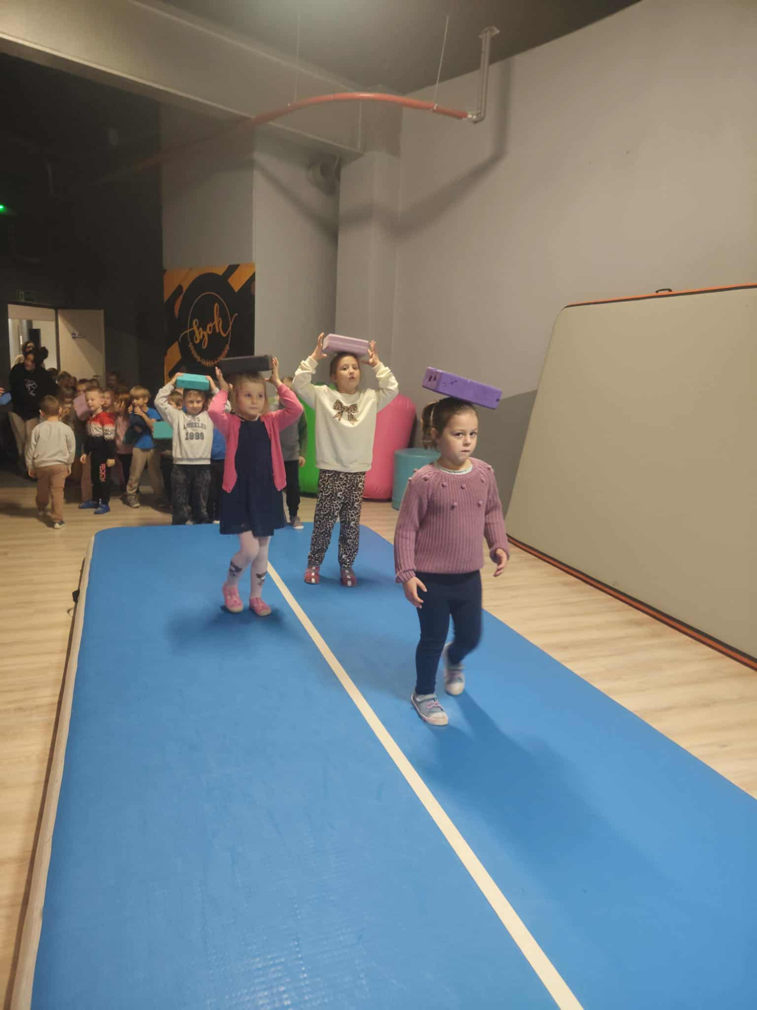 dzieci wykonuja na materacu zadania ruchowe