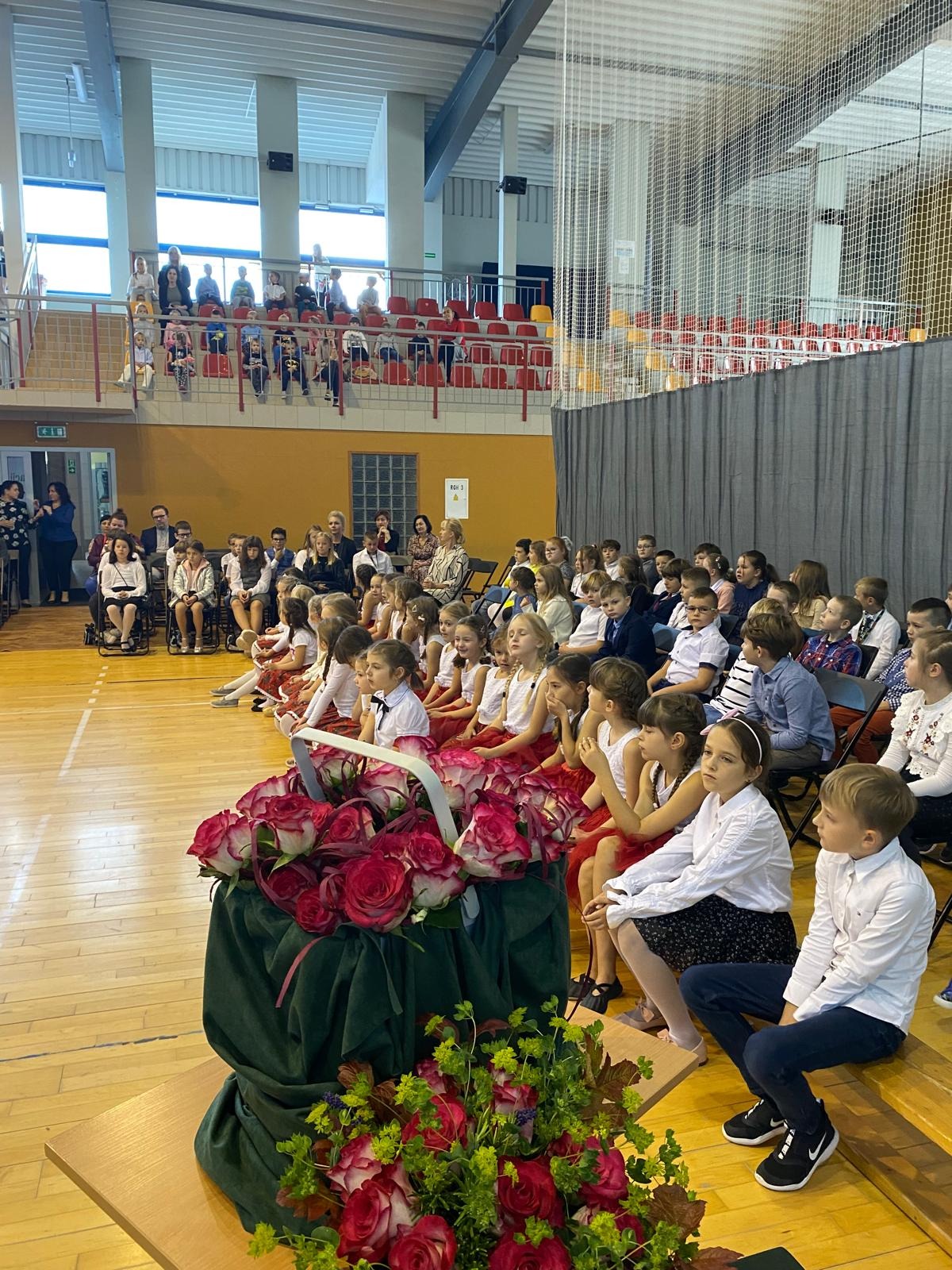 sala sportowa z siedzącymi na ławkach uczniami