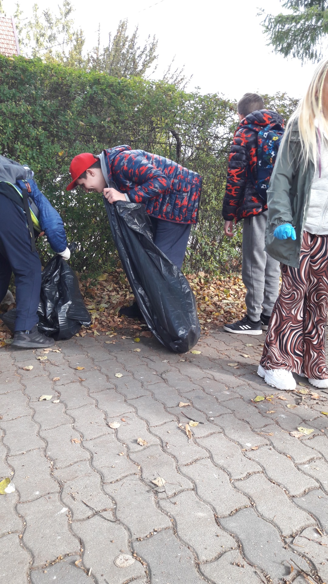 Uczniowie zbierający śmieci do worków.