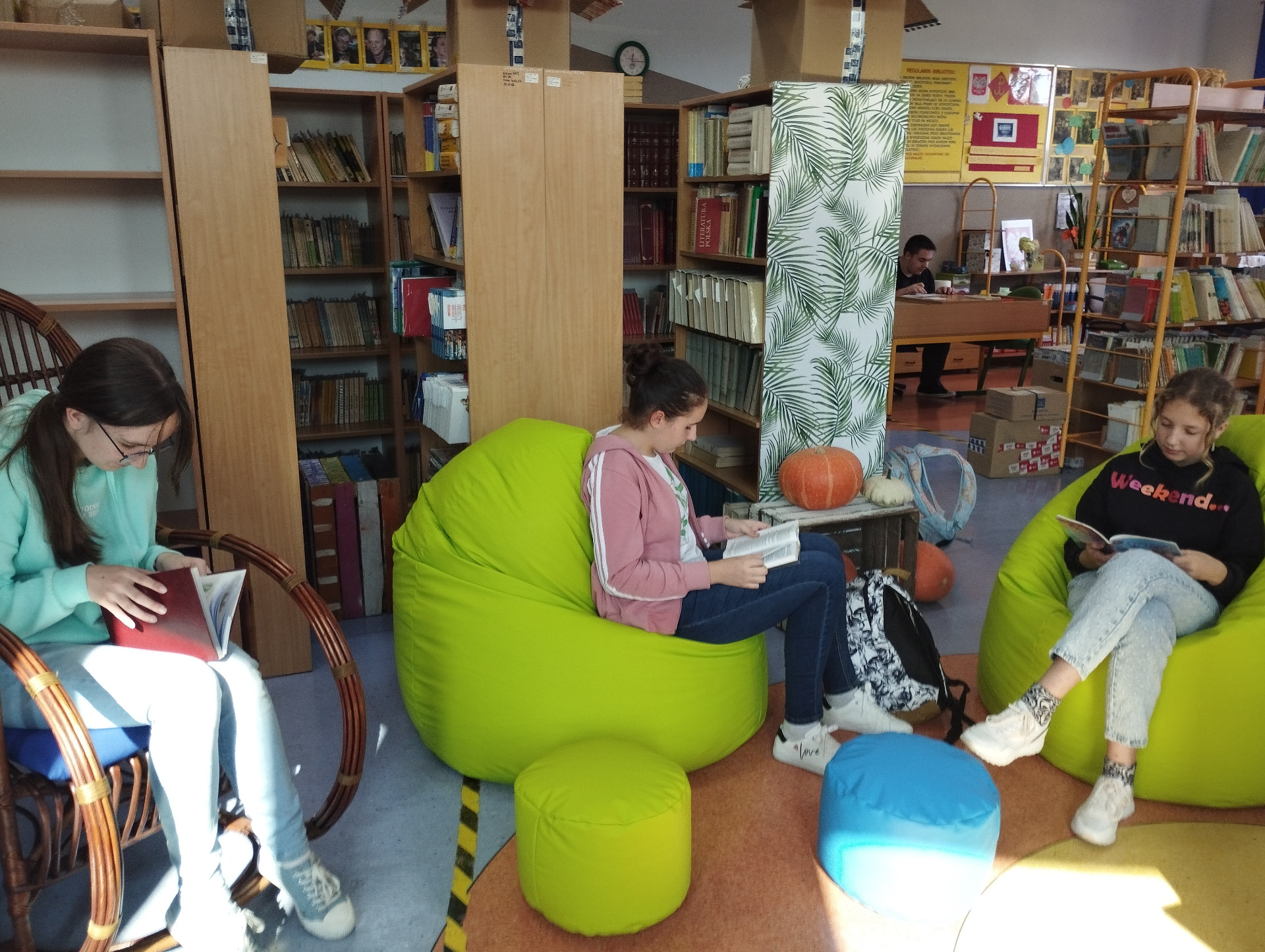 Uczennice czytają wybrane książki w czytelni bibliotecznej podczas przerwy szkolnej