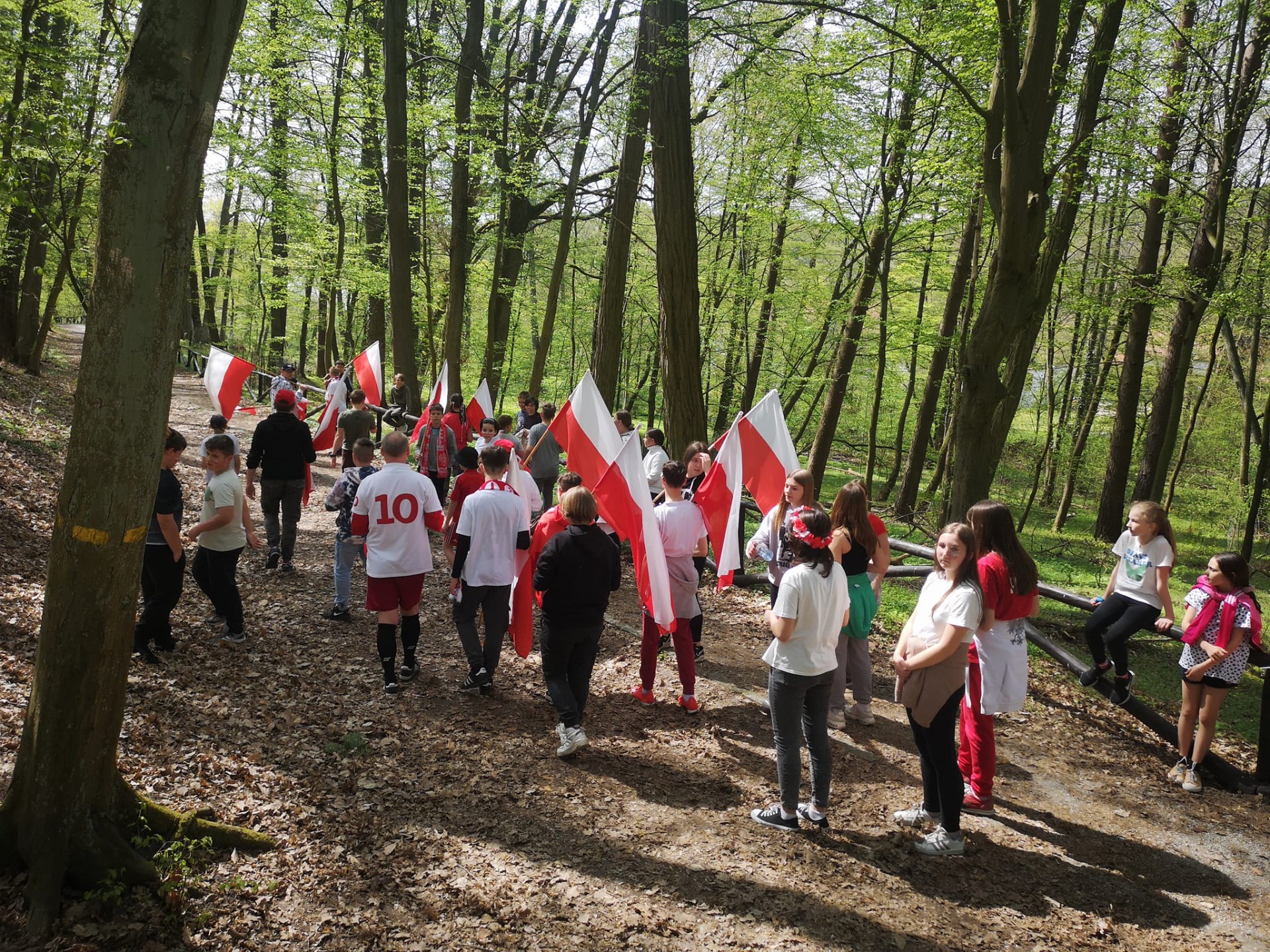 Grupa ludzi w biało-czerwonych strojach w lesie