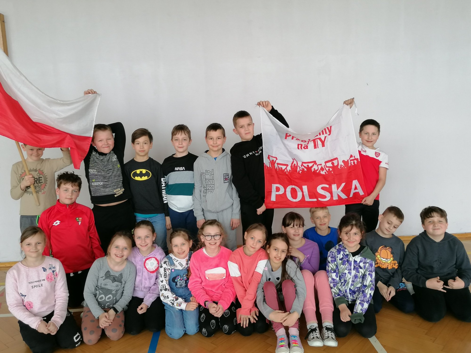 Uczniowie klasy 3 z biało-czerwonymi flagami  i z kotylionami z okazji święta Chrztu Polski
