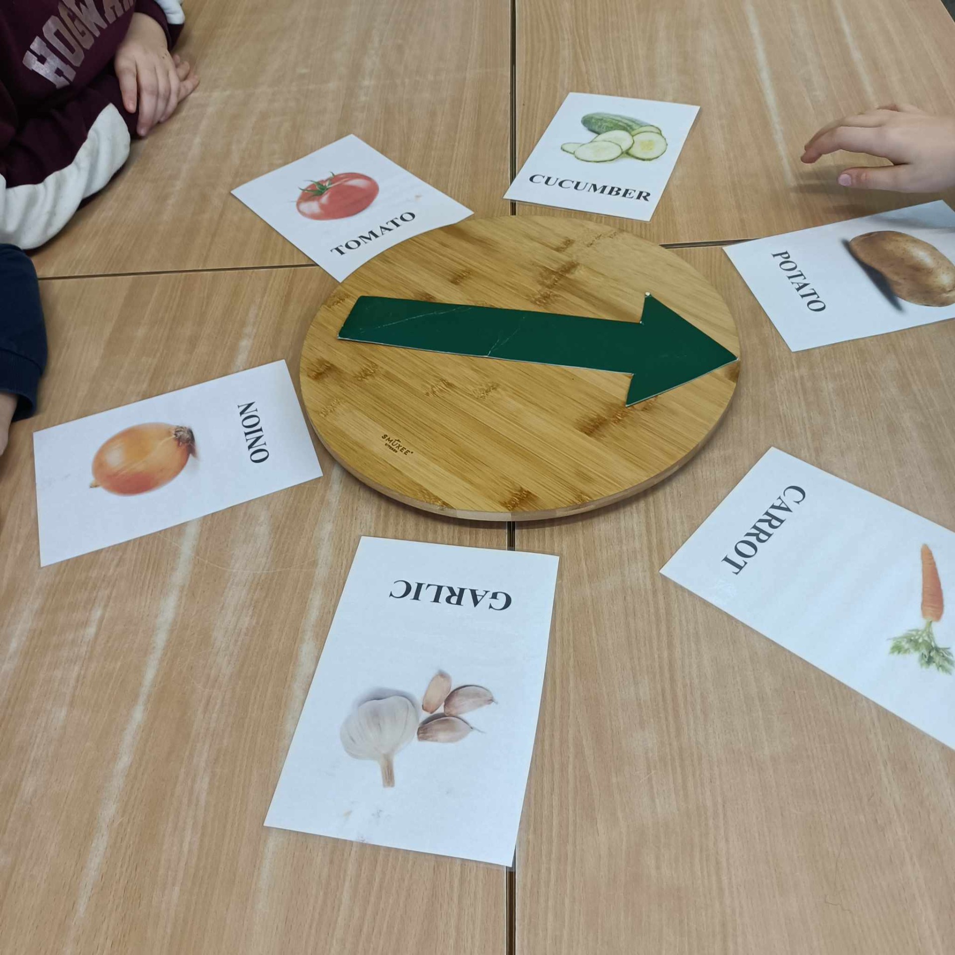 Zdjęcie przedstawia grę - drewniane koło ze strzalką. Dookoła tabliczki z nazwami i rysunkami warzyw