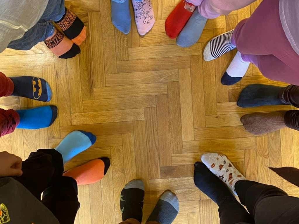 Fotografia przedstawia uczniów prezentujących na stopach kolorowe skarpetki 
