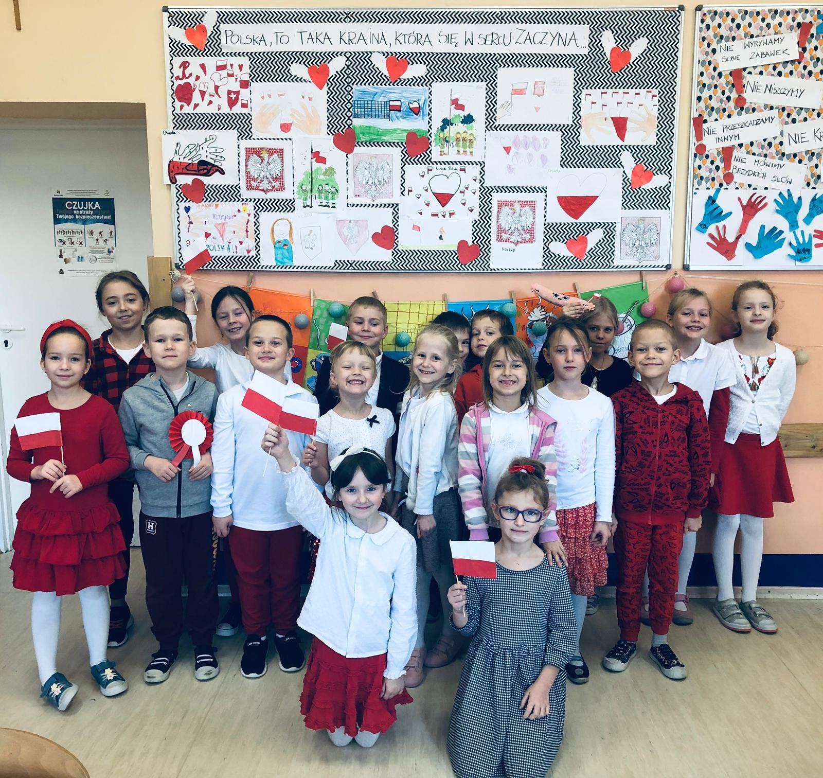 Dzieci z flagami Polski na tle gazetki z okazji Dnia Niepodległości