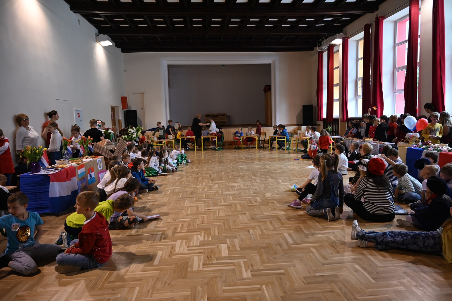 Dzieci z klas 1 i 2 zgromadzone w sali gimnastycznej w kolorowych strojach wybranego państwa UE