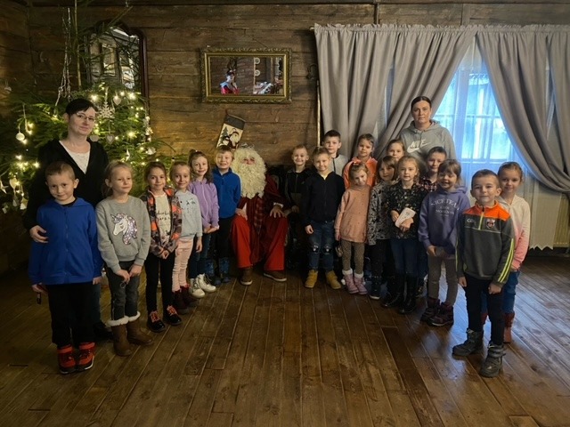 18 uczniów klasy I i dwie nauczycielki stoją wokół Świętego Mikołaja